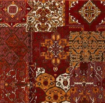 Close-up van kleurrijke patchwork meubelstof met oosterse kelimpatronen in rood, oranje, bruin, en beige. DSCO.nl